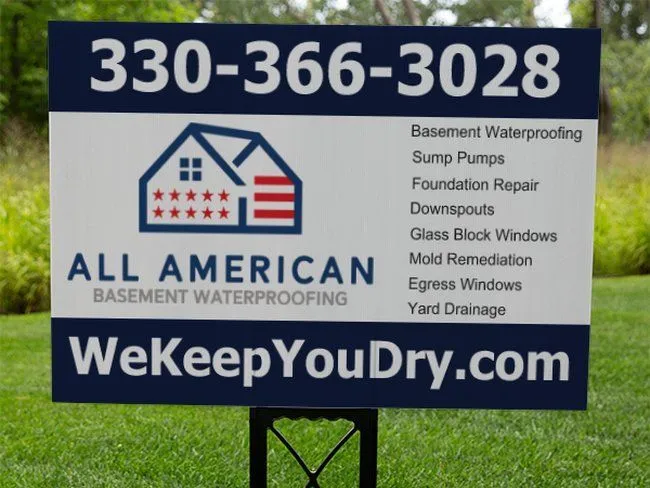 The All American Basement Waterproofing logo with a sign post in a local Ohio lawn